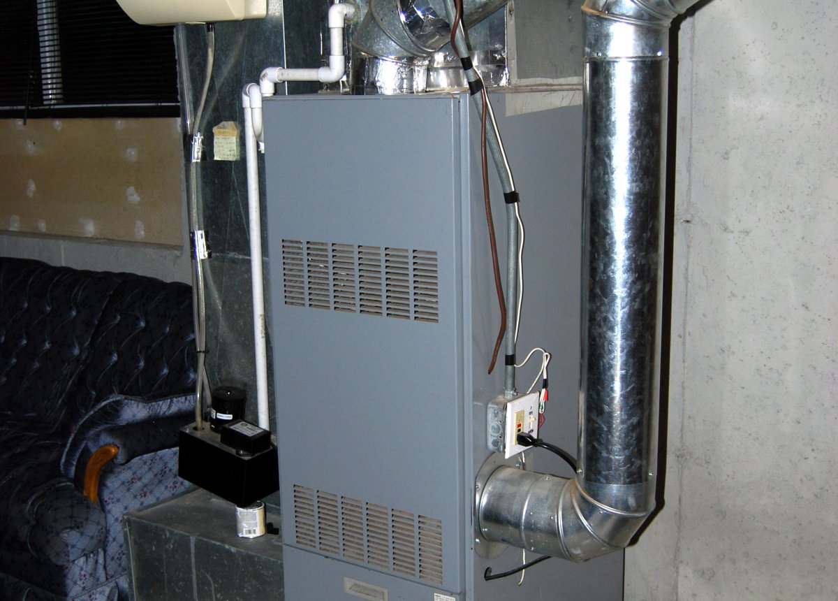 HVAC technician inspecting a noisy furnace in a Binghamton NY home during the heating season