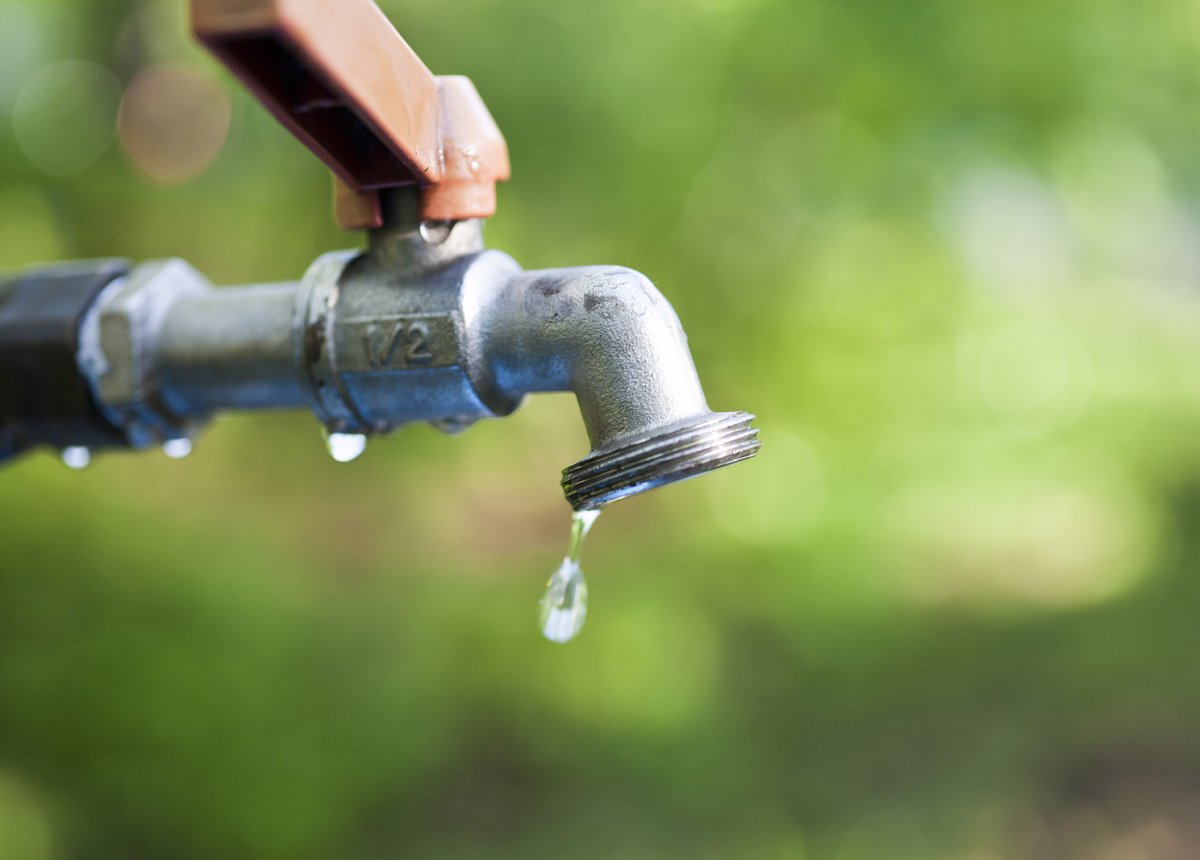 Leaking outdoor hose bib faucet dripping water on the foundation of a Binghamton NY home during summer